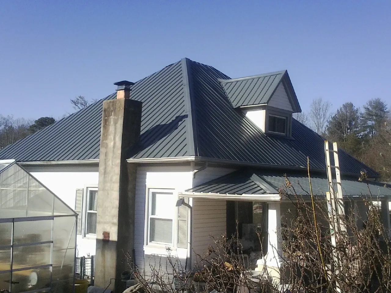 Dark blue standing seam metal roof on a white farmhouse with dormer — Slate & Tile Roof Repair by Roofing Brothers in Elmhurst