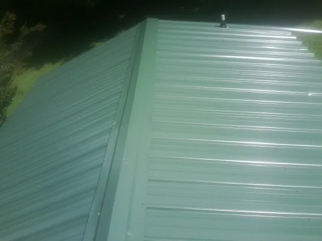 New green metal panels meeting at the ridge of a roof — Flat Roof Repair work by our crew in Elmhurst