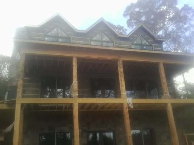 Dormers and porch framing on a large log home under construction — Roof Coating work by our crew in Elmhurst