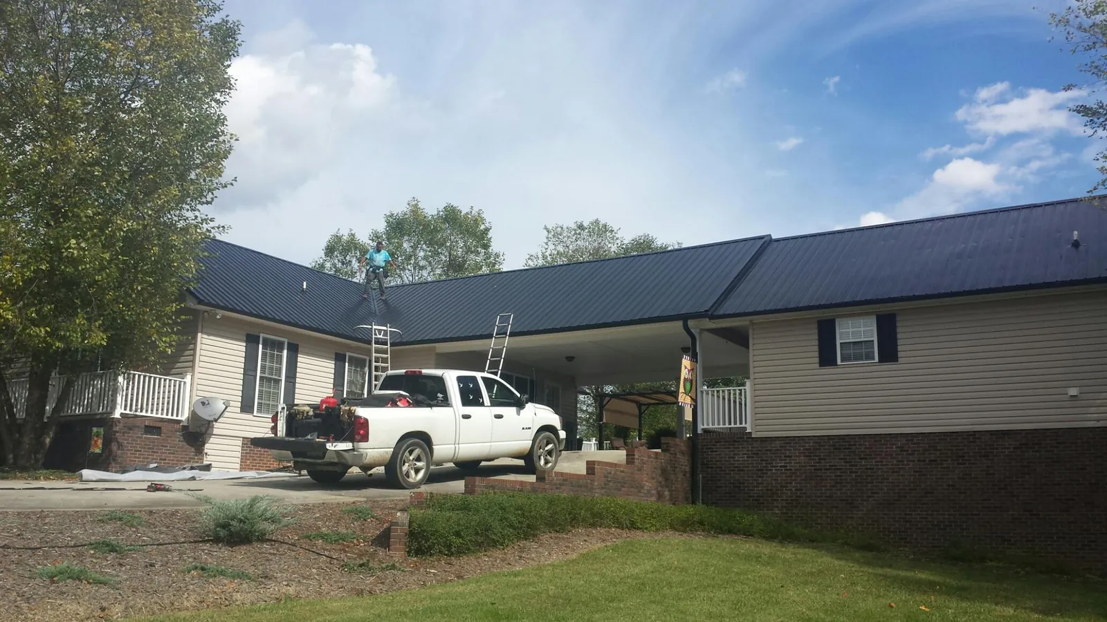 Black metal roof over a home and attached breezeway with ladders set in Elmhurst