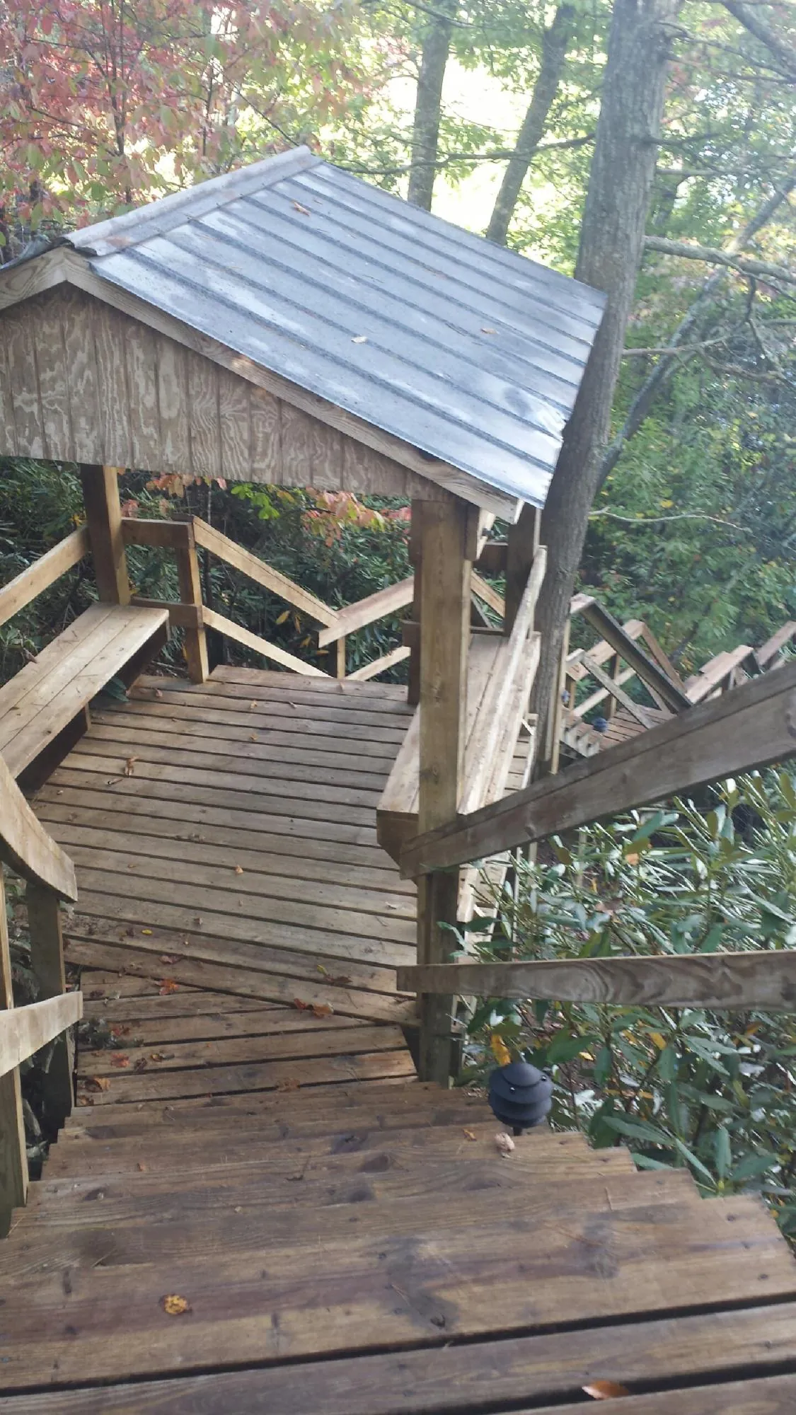 Metal roofed shelter over wooden steps on a wooded walkway — Skylight Repair & Installation work by our crew in Elmhurst