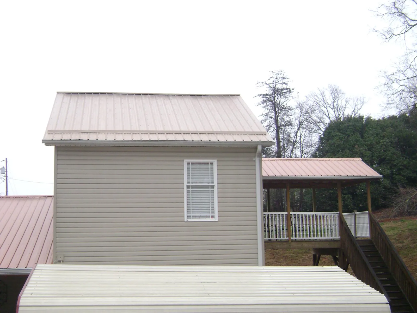 Tan metal roofs on a two story addition and attached porch, from a Roof Replacement job in Elmhurst